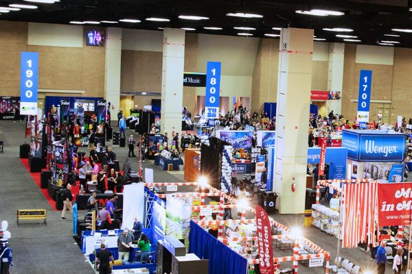 3 large blue aisle signs display numbers over a bustling convention exhibit hall