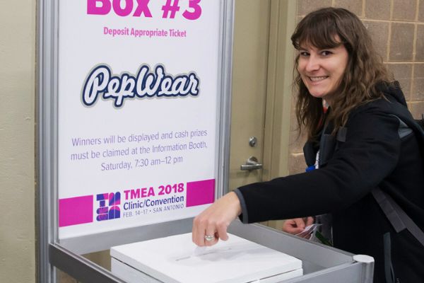 A young woman deposits a slip of paper into a box